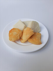 Jadah ketan, is a traditional snack from Indonesia. Made from sticky rice and grated coconut. Comparison before and after fried. On a white plate, isolated in white background