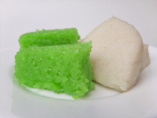 Jadah ketan (white) and wajik ketan (green), two traditional snacks from Indonesia. Made from sticky rice. On a white plate, isolated in white background