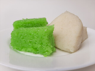 Jadah ketan (white) and wajik ketan (green), two traditional snacks from Indonesia. Made from sticky rice. On a white plate, isolated in white background