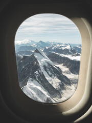 View from airplane window over snowy mountain range