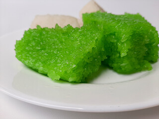 Jadah ketan (white) and wajik ketan (green), two traditional snacks from Indonesia. Made from sticky rice. On a white plate, isolated in white background