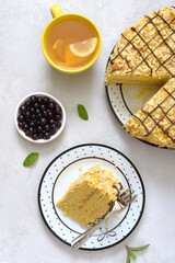 Classic Napoleon cake. Delicious festive layered dessert with puff pastry and custard decorated with fresh berries, and cup of lemon tea. The top view