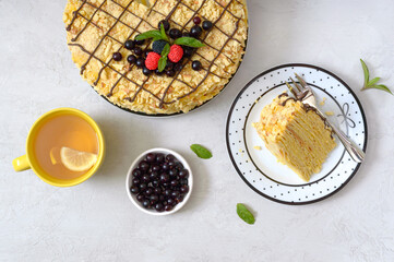Classic Napoleon cake. Delicious festive layered dessert with puff pastry and custard decorated with fresh berries, and cup of lemon tea. The top view