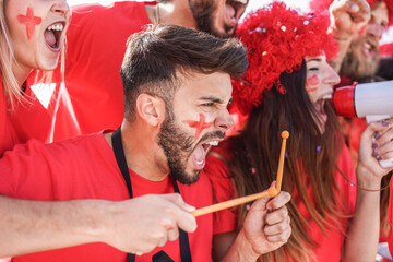 Red sport fans screaming while supporting their team out of the stadium - Football people...