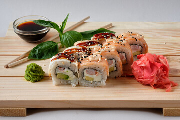 Japanese sushi rolls with Fish avocado,  cheese, wasabi, soy sauce, and marinated ginger. Tasty and artistic food for restaurant, cafe menu. Roll on wooden board.