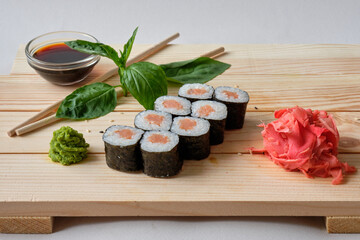 Japanese sushi rolls with Fish avocado,  cheese, wasabi, soy sauce, and marinated ginger. Tasty and artistic food for restaurant, cafe menu. Roll on wooden board.