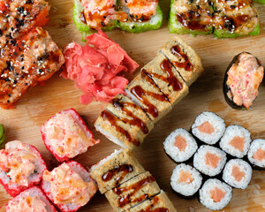 Fresh assorted Japanese sushi rolls with pickled ginger and wasabi on the wooden board. Restaurant or cafe menu images. Food photography. Top view.
