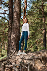Naklejka na ściany i meble Very beautiful young woman in coniferous forest in summer in hot sunny weather