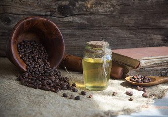 Glass bottle with cedar oil on a bacground of a wooden mortar with pine nuts and books.