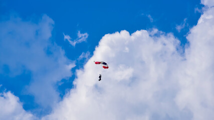 Naklejka na ściany i meble Skydiver and colorful parachute on the blue sky 