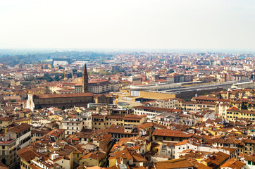 Fototapeta na wymiar Florence, Italy. An aerial view of the city landscape seen from the bell tower of Santa Maria del Fiore church. Here you can see the train station surrounded by the typical red roofs of the town