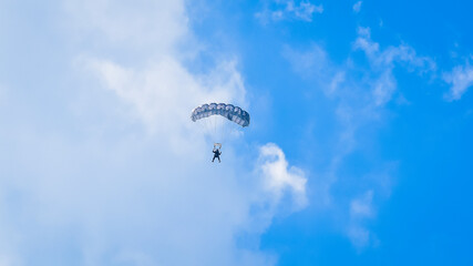 Skydiver and colorful parachute on the blue sky 