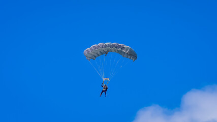 Skydiver and colorful parachute on the blue sky 