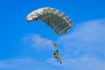 Skydiver and colorful parachute on the blue sky 