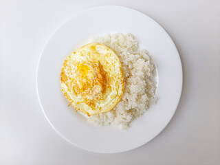 Fried egg or overcooked sunny side up, served with white rice, on a white plate, isolated in white background