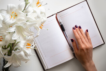 Open journal black pen, bouquet of Lily flowers with hands on a white background
