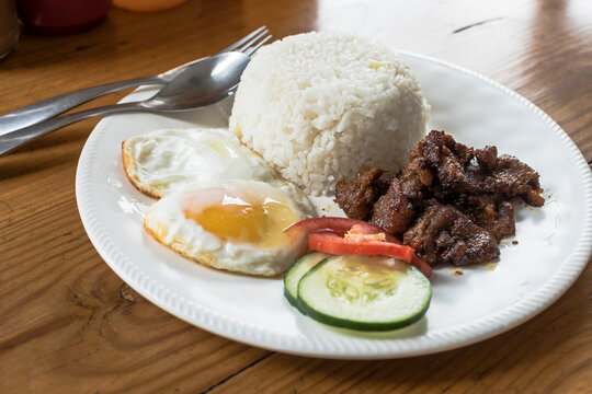 Tosilog (Tocilog): Filipino Breakfast composed of Tocino (cured meat), garlic rice (sinangag) and egg. with cucumber and tomato garnish.