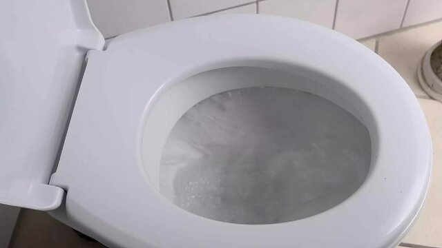 Office toilet is flushed in tiled bathroom