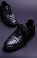 Fashionable genuine leather sneakers on a black background. Fashionable footwear.
