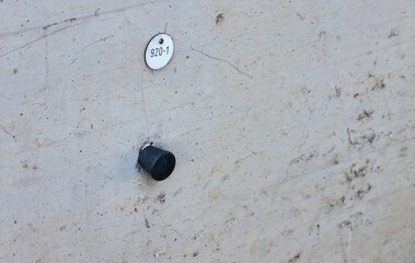 Black metal height bolt with the number 920-1 in the concrete of a bridge pier for measuring heights