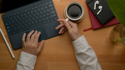 Female entrepreneur left hand using digital tablet and right hand holding coffee cup