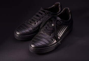 Fashionable genuine leather sneakers on a black background. Fashionable footwear.