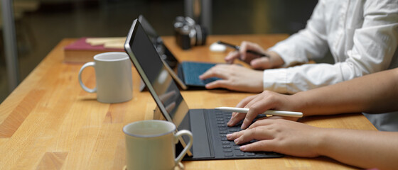 Two female workers working on their project with digital tablet while sitting together in office room
