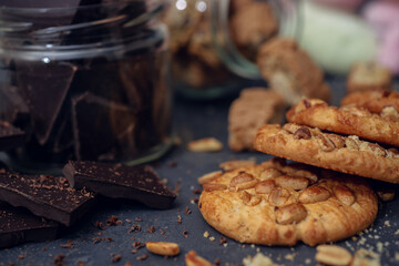 Dark chocolate and peanut cookies on dark blurred background.