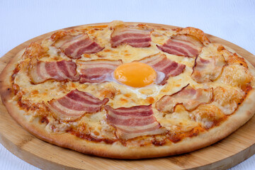 Pizza with egg, bacon and mozzarella on the wooden board. Delicious Italian food. Cafe, pizzeria and restaurant menu. More food images download in catalog.