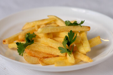 Close up sliced fried potatoes with parsley on a white plate. Food photography. 