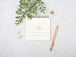 Calendar with rose gold pen and green leaf
