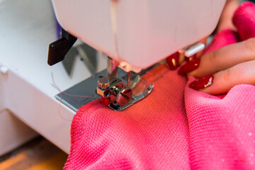 Sewing clothes in a sewing studio. Close-up of seamstress hands, material and needle of a sewing...