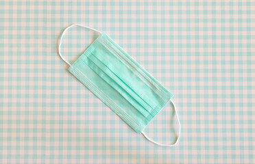 Teal colored face mask lying on a teal colored checkered surface