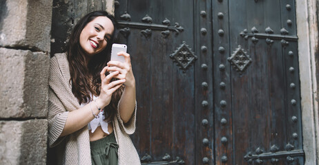 Charming brunette woman millennial using smartphone for making picture enjoying free time outdoors, positive female blogger shooting video for share with followers generation z in social media