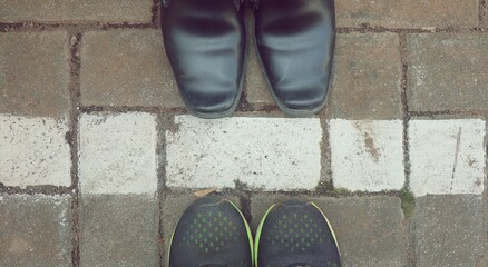 Formal shoes and sport shoes on asphalt, top view on white lines