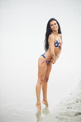Obraz premium A woman in a swimsuit with an American flag walks along the coast