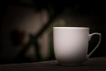 White coffee mug Empty, empty on a wooden table. The image is decorated by adding a black border beside the object.