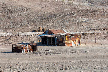 Traditional african hut from rusty sheet of tin in desert of Erongo Region. In background is...
