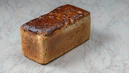 rectangular loaf of wheat bread with a baked shiny crust on the kitchen table.