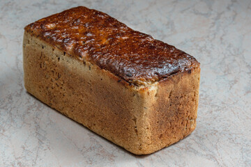 rectangular loaf of wheat bread with a baked shiny crust on the kitchen table.