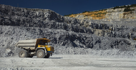 Mining dump truck in limestone quarry, panorama.