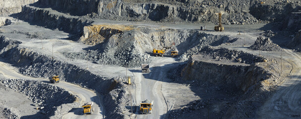 Large number of heavy mining machinery operating in a limestone quarry, industrial panorama.