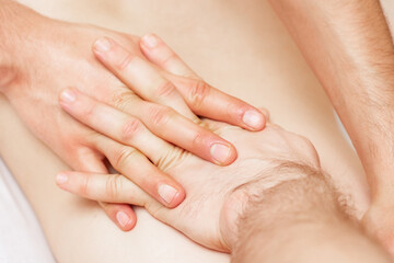 Woman receiving back massage with hands of male therapist.