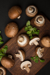 Fresh champignon mushrooms on a cutting board and on a black background