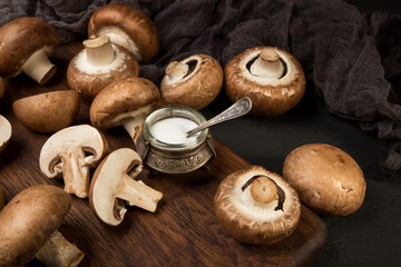 Fresh champignon mushrooms on a cutting board and on a black background