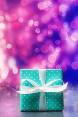 Blue gift box against blue-pink defocused holiday lights