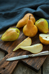 Naklejka na ściany i meble Pears on a cutting board and old wooden background.
