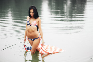 Cheerful woman celebrating US Independence Day on the beach with American flag