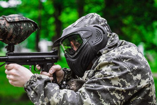 Closeup Portrait of Paintball Player In Full Gear At The Shooting Range with Paintball marker in Protective Mask and Camouflage Pixels