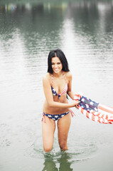 Cheerful woman celebrating US Independence Day on the beach with American flag